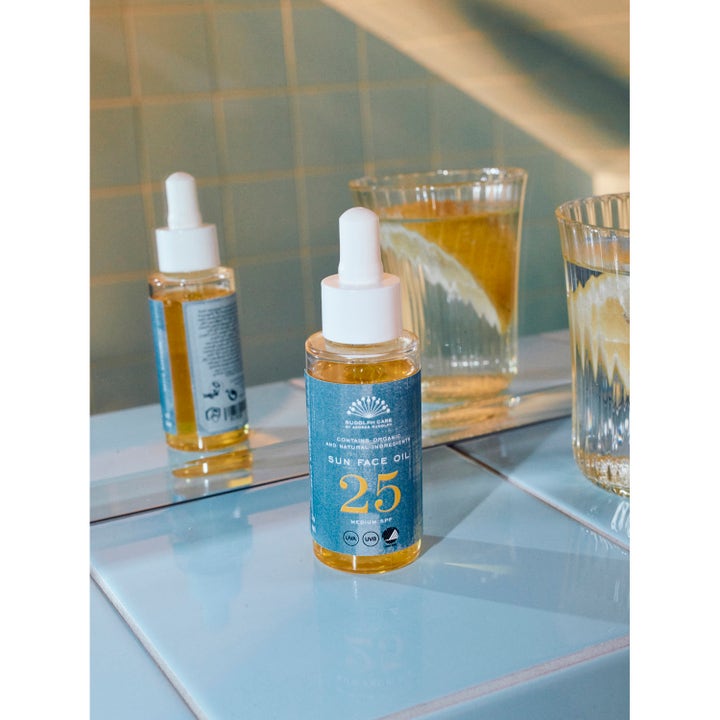 Rudolph Care Sun Face Oil 50 ml beskyttende ansiktsolje SPF 25 i glassflaske med pipette på lyseblå fliser