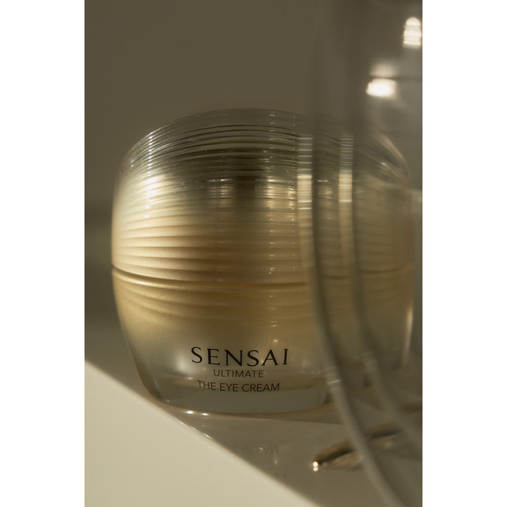 Sensai Ultimate The Eye Cream 15 ml øyekrem som gir glød i en elegant gullfarget krukke med riller.
