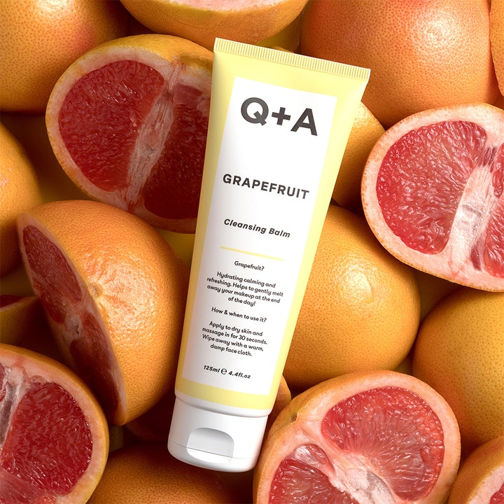 Q+A Grapefruit Cleansing Balm 125 ml fuktighetsgivende ansiktsrengjøring i gul tube omgitt av friske grapefrukter.
