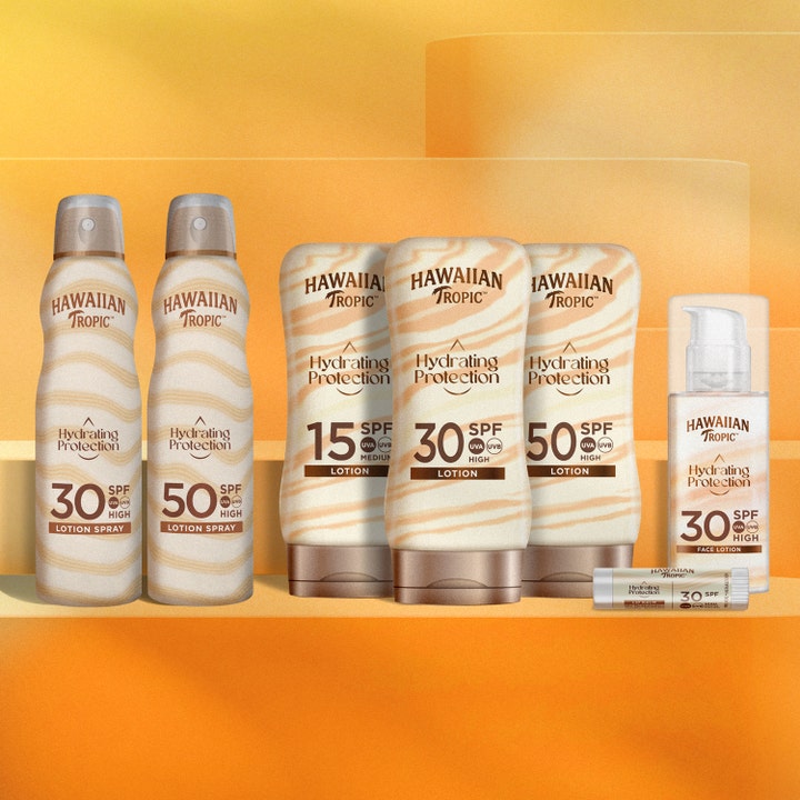 Hawaiian Tropic Hydrating Protection C-Spray SPF50 220 ml fuktighetsgivende solspray i en serie på oransje bakgrunn
