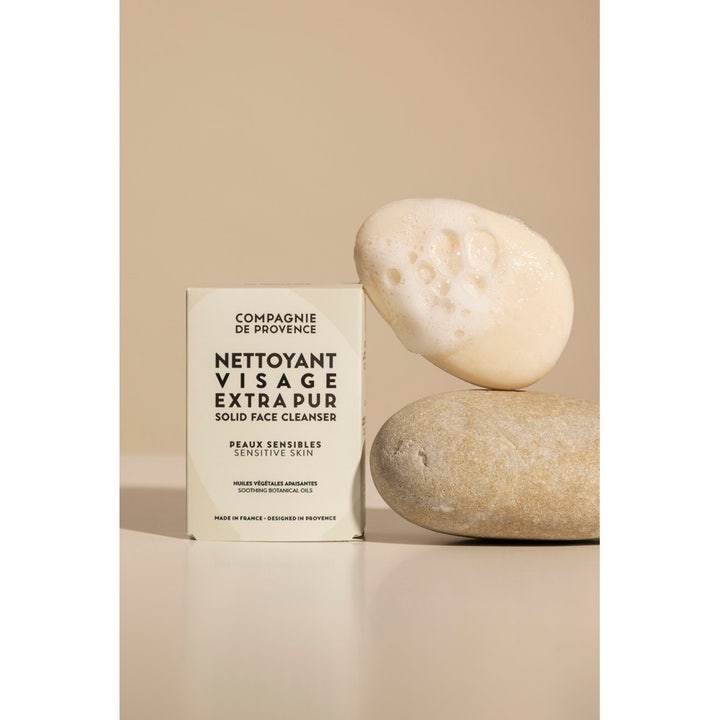Compagnie de Provence Solid Face Cleanser 85 g beroligende ansiktsrens ved siden av steiner og skum