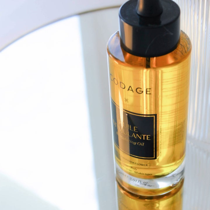 Codage Paris Stimulating Oil 100 ml stimulerende kroppsolje i glassflaske med sort pipette på en speilflate