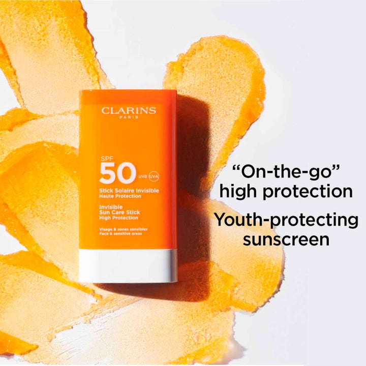 Clarins Invisible Sun Care Stick SPF50 17 g solkrem i oransje hylse med oransje produktstrøk i bakgrunnen