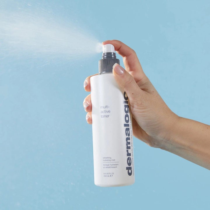 Dermalogica Multi-Active Toner 250 ml fuktighetsgivende ansiktsspray i hvit flaske som sprayes av en hånd mot blå bakgrunn