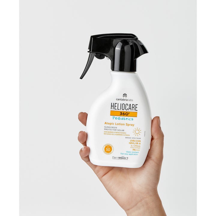 Heliocare Pediatrics Atopic Lotion Spray 250 ml SPF 50 solkrem i hvit sprayflaske som holdes i en hånd