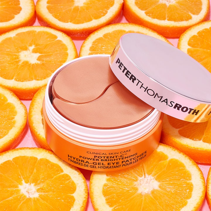 Peter Thomas Roth Potent-C Eye Patches 90 g opplysende øyemasker i oransje krukke omgitt av friske appelsinskiver.