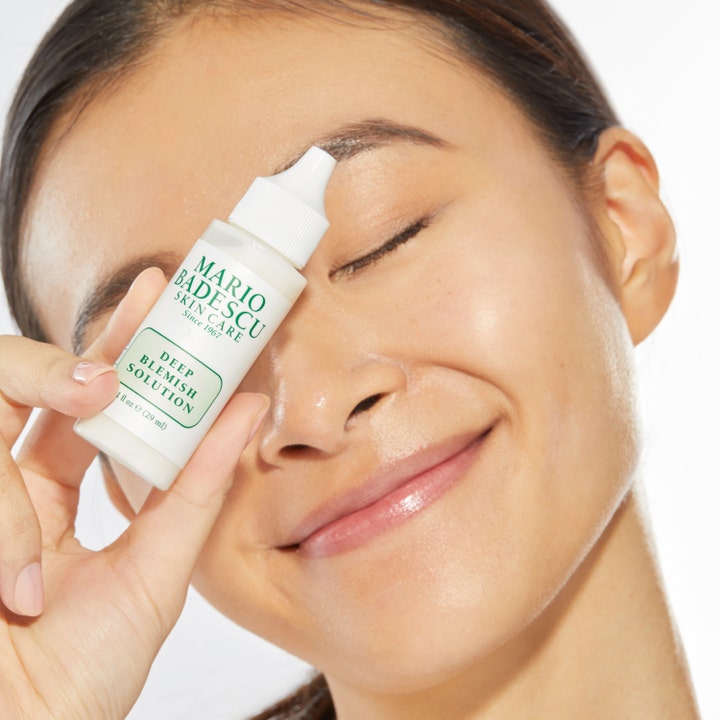 Mario Badescu Deep Blemish Solution 29 ml spot treatment mot urenheter i hvit plastflaske som holdes av en kvinne