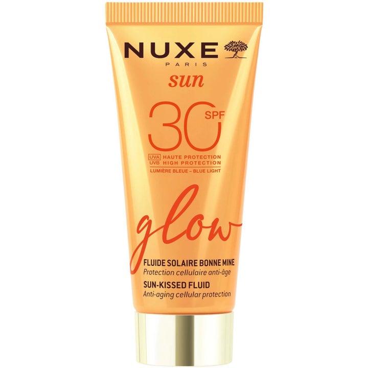 Nuxe Sun Glow SPF 30 Sun-Kissed Fluid beskyttende solkrem i oransje tube med gullfarget kork som gir huden glød