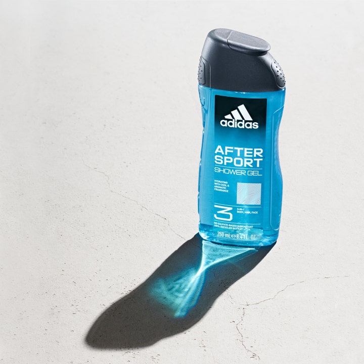 Adidas After Sport 250 ml fuktighetsgivende dusjsåpe i blå flaske som kaster en klar blå skygge på grått underlag.