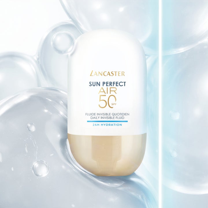 Lancaster Sun Perfect AIR 40 ml SPF 50 fuktighetsgivende solkrem i hvit og gullfarget flaske omgitt av vannbobler.