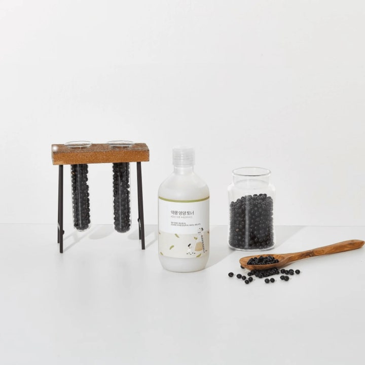 Round Lab Soybean Nourishing Toner 300 ml er et næringsgivende ansiktsvann ved siden av sorte soyabønner.