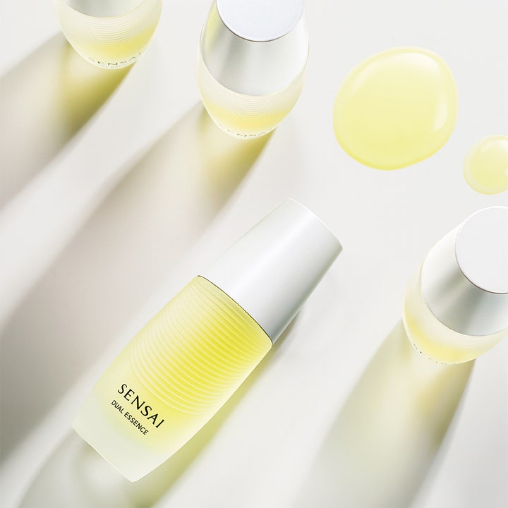 Sensai Dual Essence 30 ml glødgivende essence med gule dråper og frostet glassflaske med sølvfarget lokk