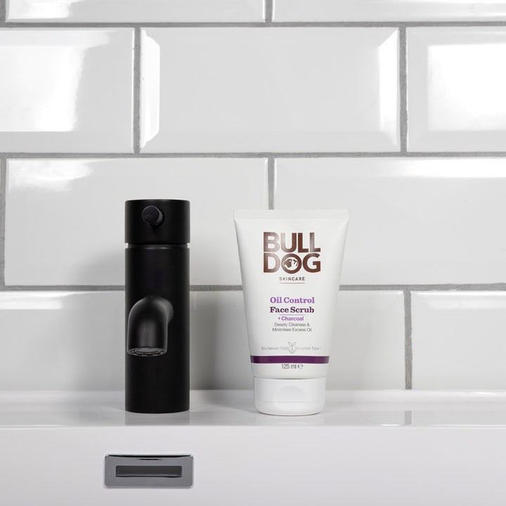 Bulldog Oil Control Face Scrub 125 ml ansiktsskrubb med kull motvirker fet hud i hvit tube ved en svart kran