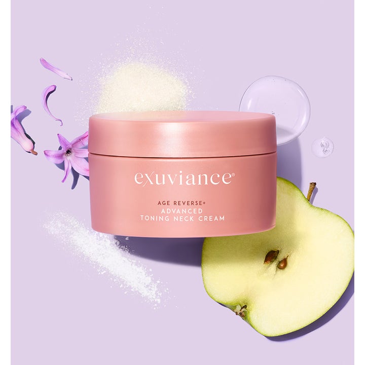 Exuviance Age Reverse Toning Neck Cream 125 g i rosa krukke med et halvt eple og lilla blomster på lilla bakgrunn.