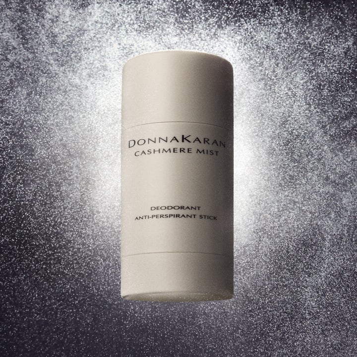 DKNY Cashmere Mist Deodorant Stick mot svette i beige hylse foran en glitrende og skimrende bakgrunn.