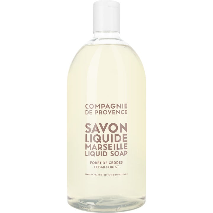 Compagnie de Provence Savon Liquide Marseille Cedar Forest rengjørende flytende såpe i stor klar plastflaske med lys gul væske.
