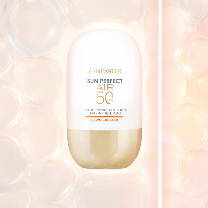 Lancaster Sun Perfect AIR Glow Booster 40 ml solkrem ansikt gir glød i en hvit og gullflaske mot lysende bobler.