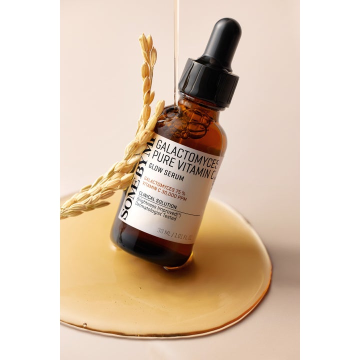 Some By Mi Galactomyces Pure Vitamin C Glow Serum 30 ml ansiktsserum i brun glassflaske i en dam av gyllen væske med kornaks
