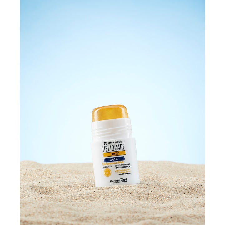 Heliocare Sport Stick SPF 50+ 25 g solstift gir høy beskyttelse med en transparent oransje stift stående i sanden.