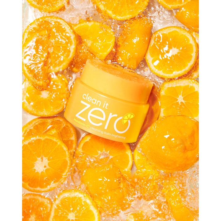 Banila Co Clean It Zero Brightening 100 ml cleansing balm i gul krukke omgitt av friske mandarinskiver i vann