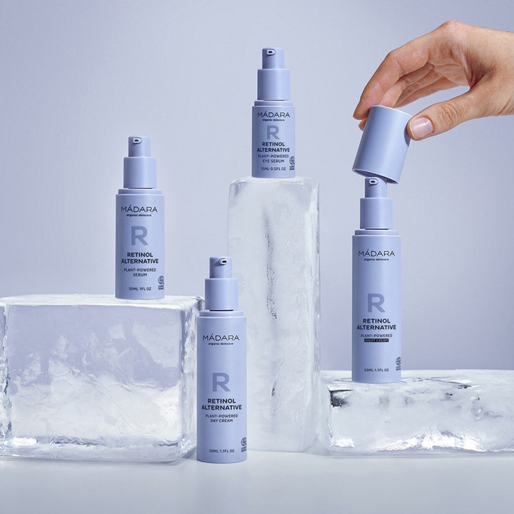 MÁDARA Retinol Alternative 50 ml hudpleie i lyseblå pumpeflasker på isblokker mens en hånd løfter av et lokk.