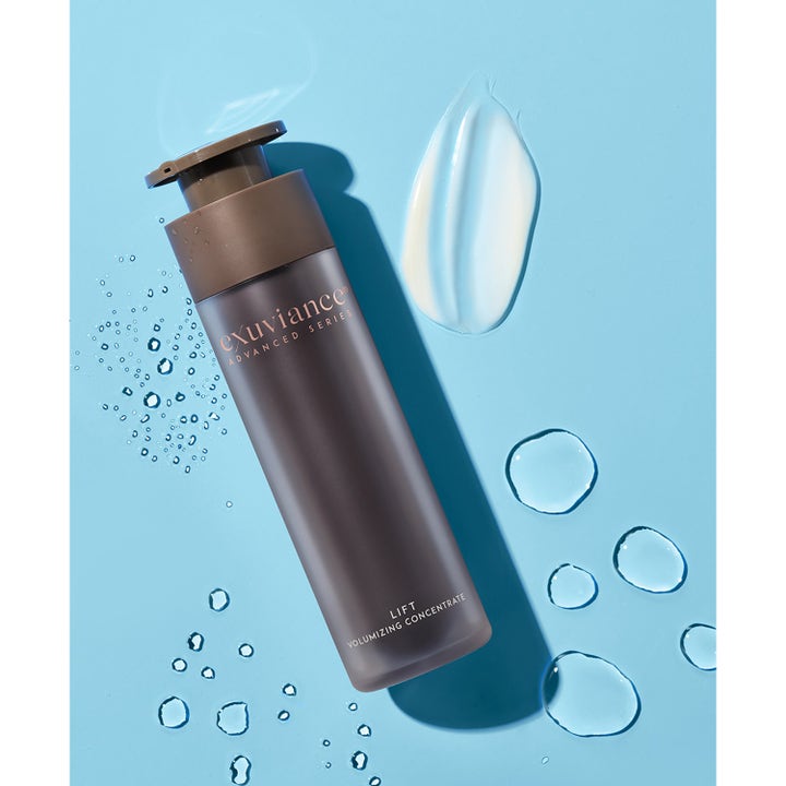 Exuviance Lift Volumizing Concentrate 50 g volumgivende serum i brun pumpeflaske med hvit kremtekstur og vanndråper