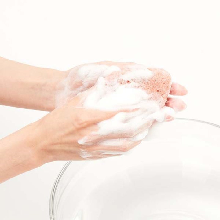 Purito JEJU Volcanic Scoria Konjac Sponge 7 g dyprensende svamp som skaper et rikt hvitt skum mellom hendene.