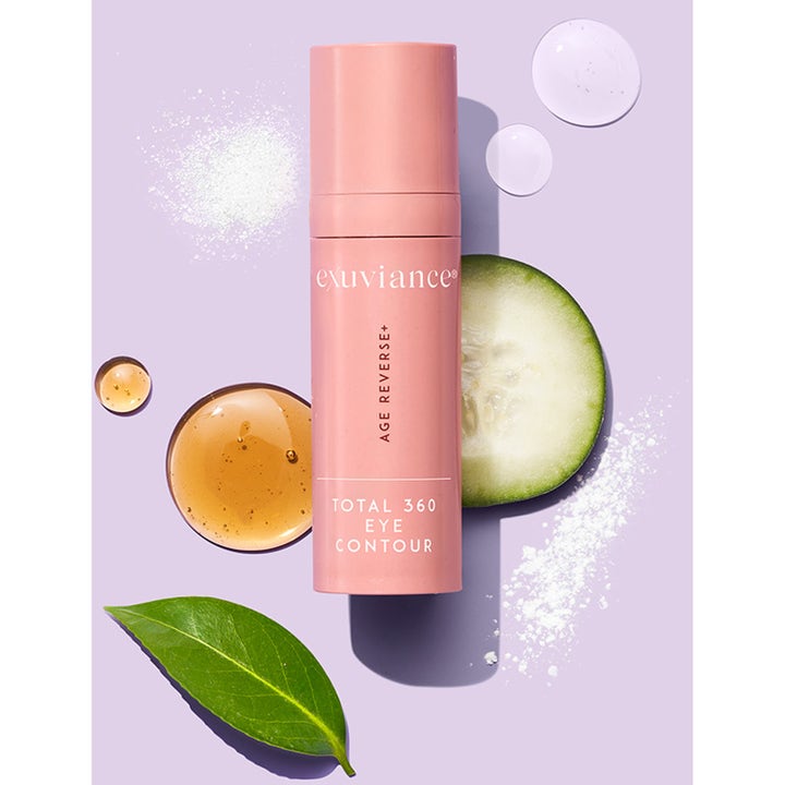 Exuviance Age Reverse Eye Contour 15 g øyekrem i rosa pumpeflaske med agurk og serumdråper på lilla bunn.