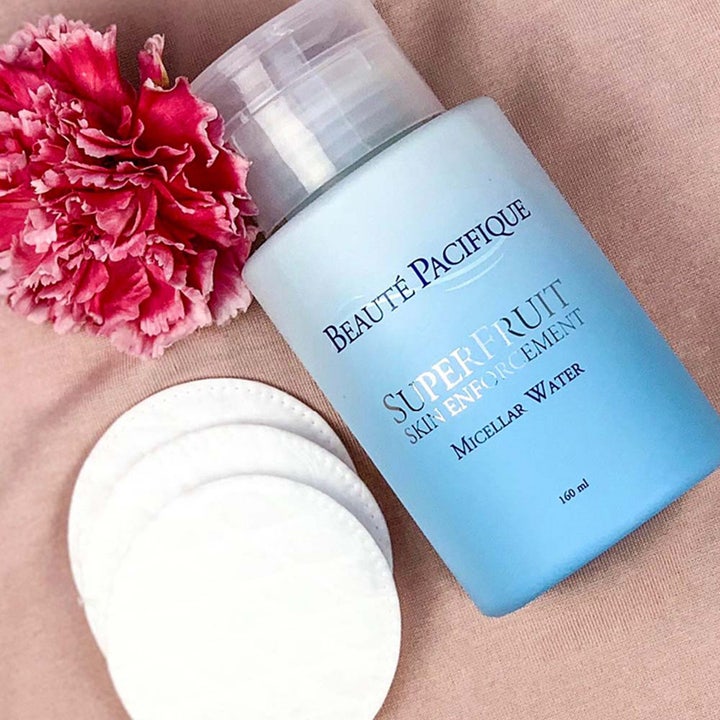 Beauté Pacifique Superfruit Micellar Water 160 ml ansiktsrens i lyseblå flaske ved bomullspads og en rosa nellik.