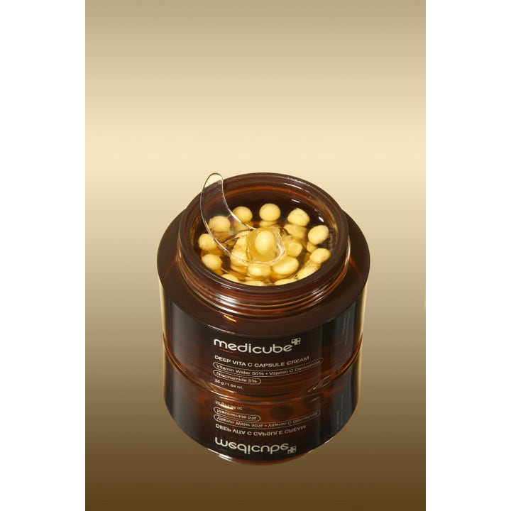 Medicube Deep Vita C Capsule Cream 55 g opplysende ansiktskrem med niacinamid og gule kapsler i en åpen brun krukke.