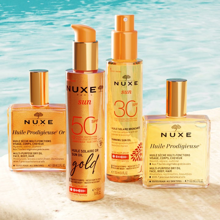 Nuxe Sun Tanning Oil Gold 150 ml solkrem til kropp i oransje pumpeflaske i en setting ved et basseng.