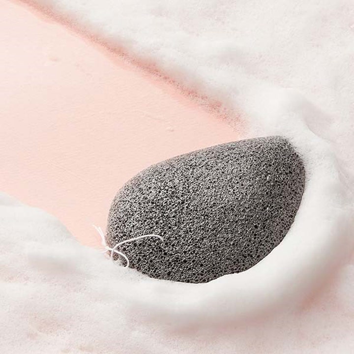 Purito JEJU Volcanic Scoria Konjac Sponge 7 g ansiktsbørste i grå porøs tekstur omgitt av hvitt renseskum