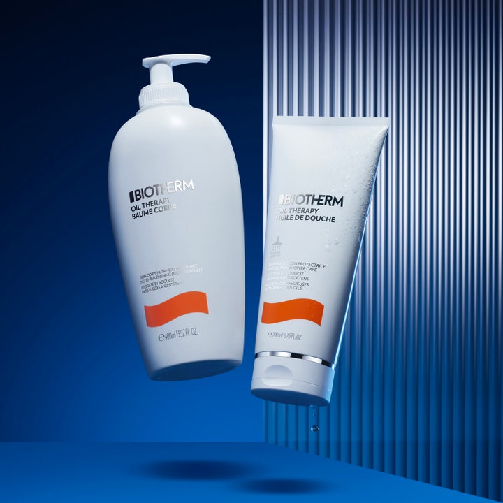 Biotherm Oil Therapy 200 ml fuktighetsgivende dusjsåpe i hvit tube med vanndråper og hvit pumpeflaske på blå bakgrunn.