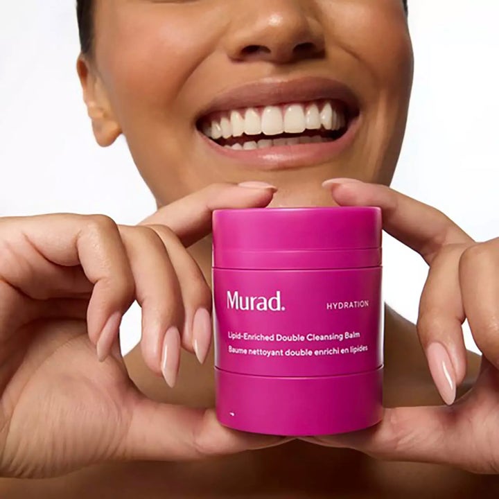Murad Lipid-Enriched Double Cleansing Balm 50 ml fuktighetsgivende ansiktsrens i rosa krukke holdt av en smilende person