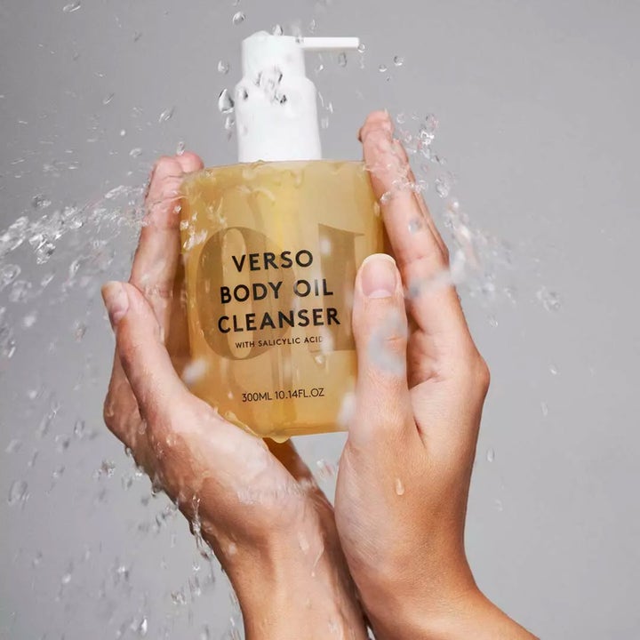 Verso N°10 Body Oil Cleanser 300 ml dusjolje med salisylsyre som holdes i hender omgitt av vannsprut