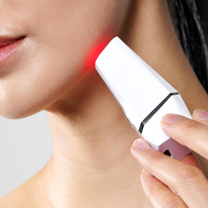 Currentbody Skin LED Blemish Pen hudpleieapparat mot urenheter som lyser rødt mot huden på kjeven.