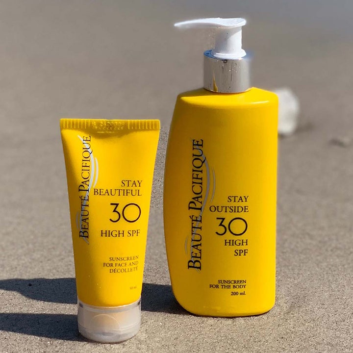 Beauté Pacifique Stay Outside SPF30 Body 200 ml solkrem i gul pumpeflaske og tube på en sandstrand