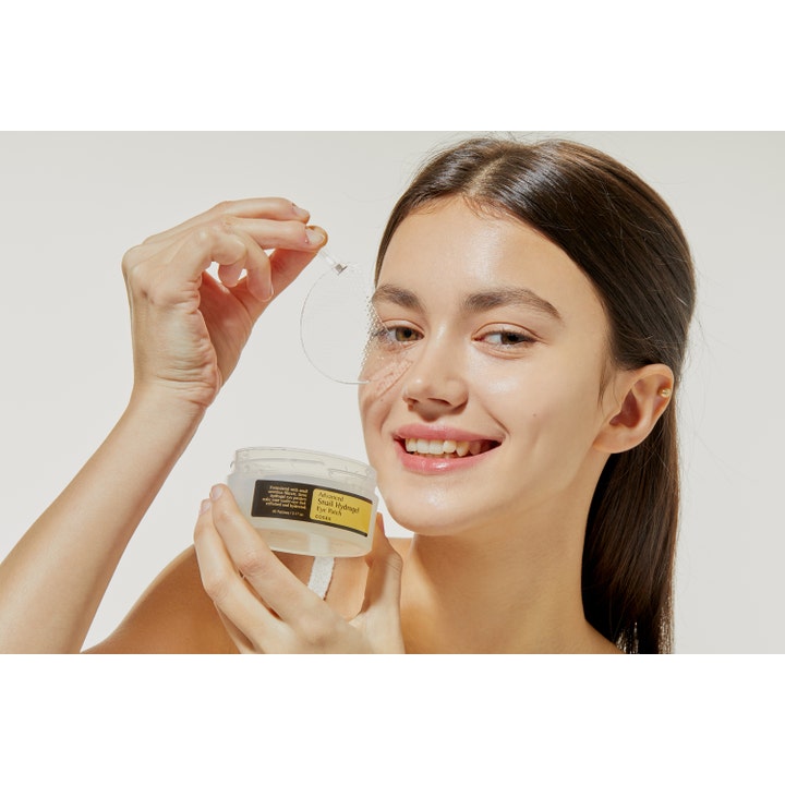 COSRX Advanced Snail Hydrogel Eye Patches 60 stk fuktgivende øyemasker kvinne som holder en gjennomsiktig patch