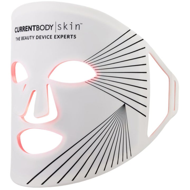 CurrentBody Skin LED Light Therapy Mask som forbedrer hudtekstur er en hvit silikonmaske med rødt lys og svarte mønstre.