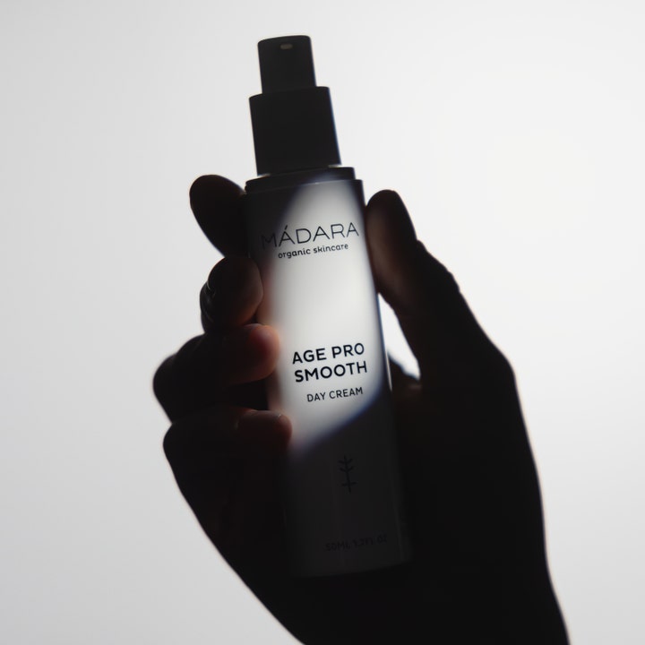 MÁDARA AGE PRO Smooth Day Cream 50 ml glattende dagkrem i hvit flaske med pumpe som holdes i en hånd.