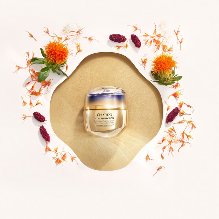 Shiseido Vital Perfection Concentrated Supreme Cream 50 ml oppstrammende dagkrem i gullkrukke blant oransje blomster
