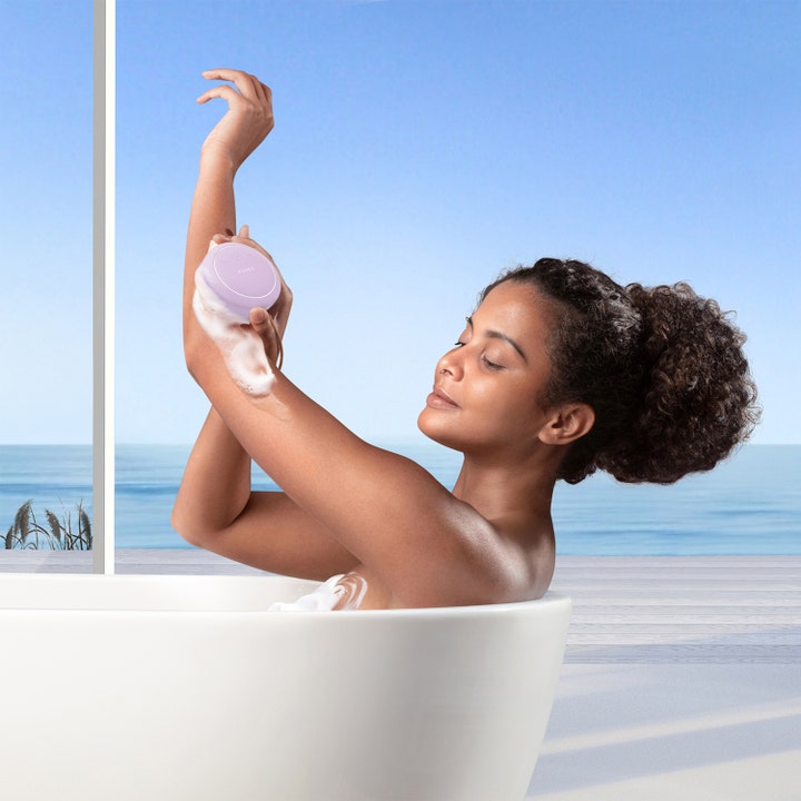 FOREO LUNA 4 body Lavender 1 stk eksfolierende kroppsbørste i bruk av kvinne i et avslappende bad