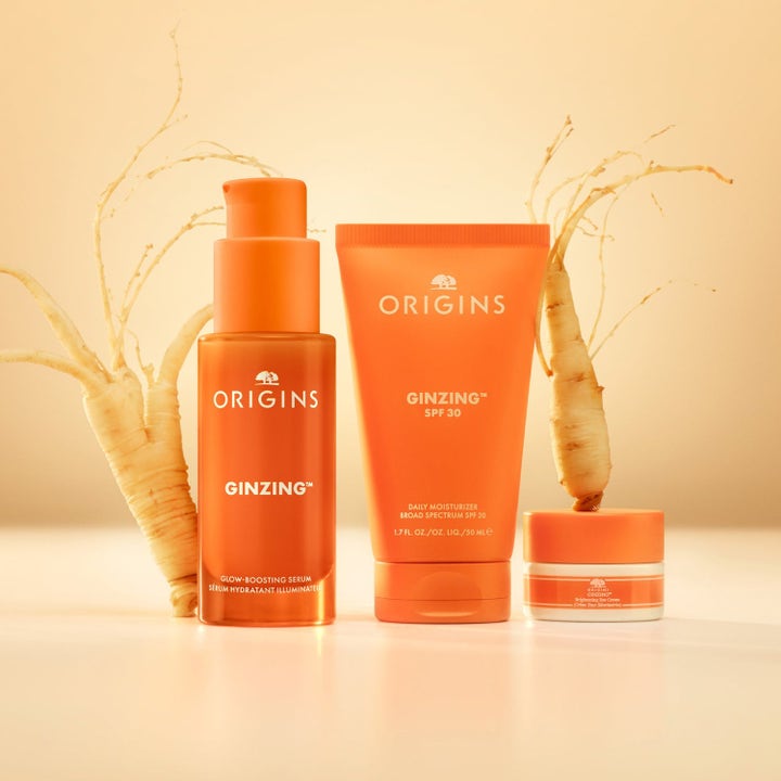 Origins Glow Getter 45 ml glødgivende sett med oransje GinZing serum tube og krukke ved siden av ginsengrøtter