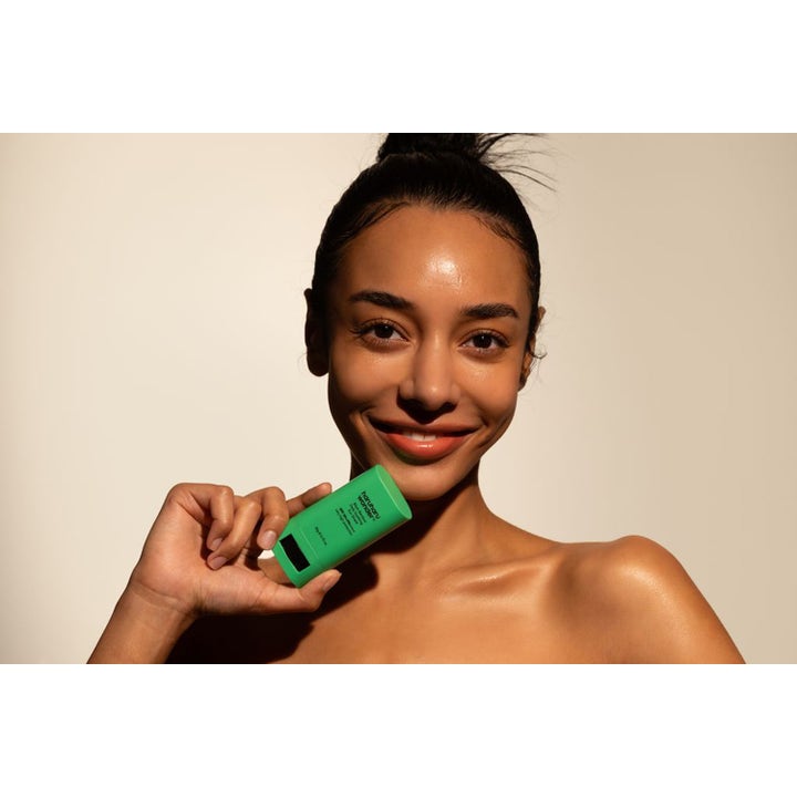 haruharu wonder Black Bamboo Daily Soothing Sun Shield 20 g beroligende solstift holdt av kvinne med glødende hud