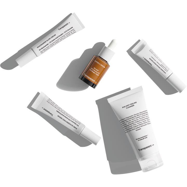 Niche Beauty Lab Transparent Lab Discovery Kit hudpleiesett for fukt og glød med hvite tuber og en brun glassflaske.