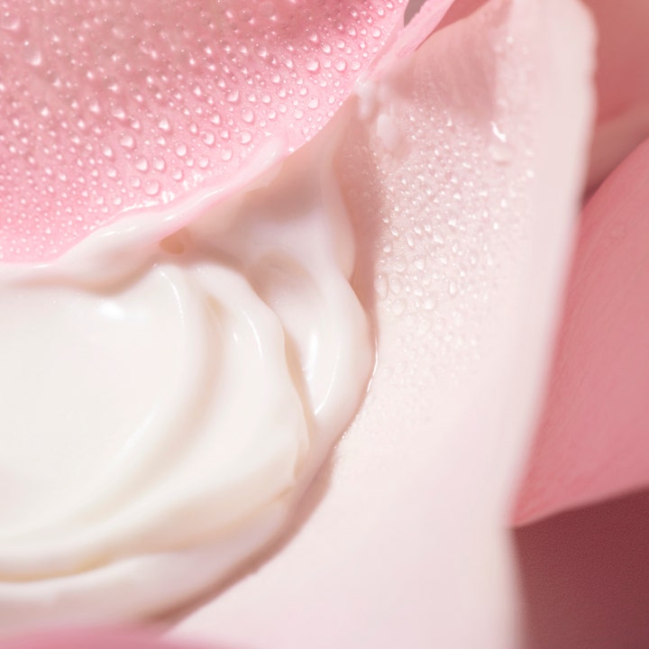 Nuxe Very Rose Makeup Removing Milk 200 ml sminkefjerning med hvit kremet konsistens på fuktige roseblader