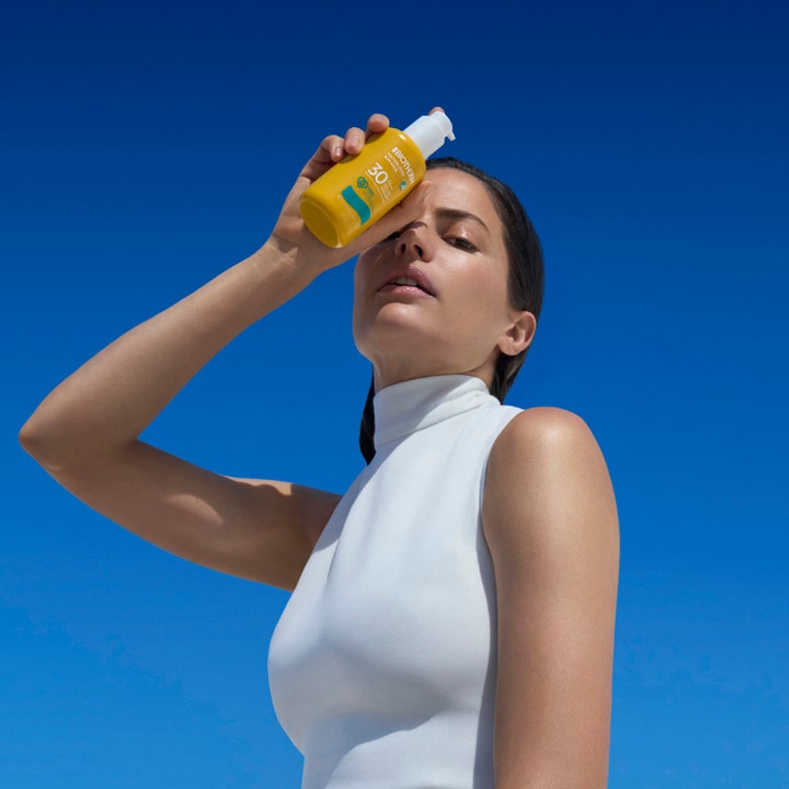 Biotherm Waterlover Sun Milk SPF30 200 ml fuktighetsgivende solkrem holdt av kvinne mot en skyfri blå himmel