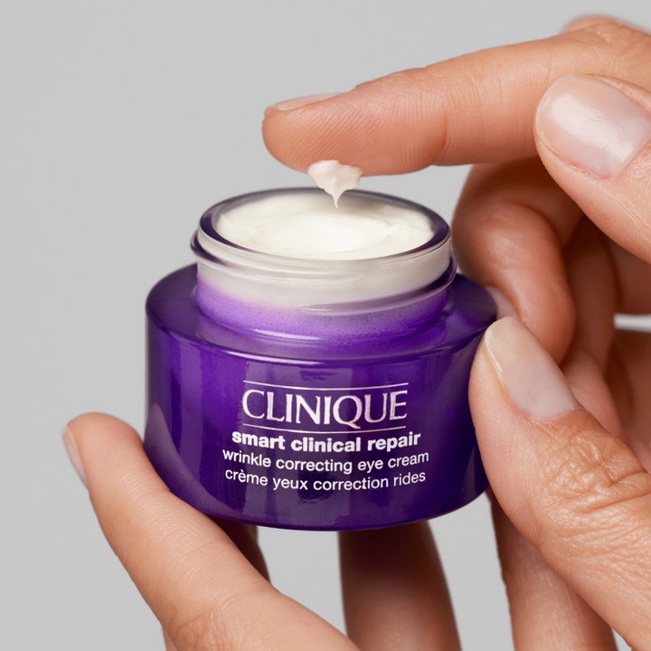 Clinique Smart Clinical Repair 15 ml rynkekorrigerende øyekrem i lilla krukke med hvit krem på en fingertupp.