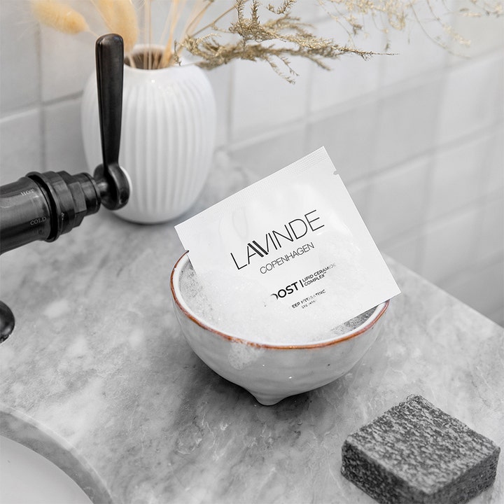 Lavinde Copenhagen Boost Deep Hydrating Eye Mask 2 stk fuktighetsgivende øyemaske hvit sachet i en skål på marmorbenk
