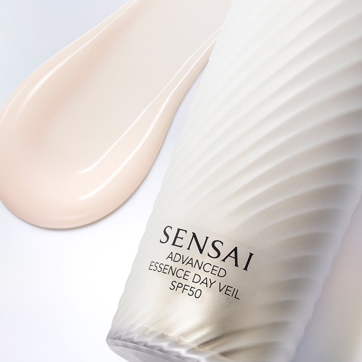 Sensai Advanced Essence Day Veil 40 ml serum med SPF 50, hvit riflet flaske og lyst rosa kremtekstur.
